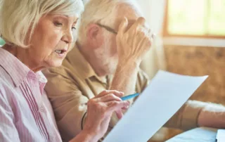 Two seniors going over their finances and struggling, a sign that they may need the help of daily money managers for seniors.