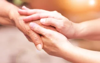 Close-up of a caregiver holding an older adult’s hand, showing trust and care from a professional fiduciary in California.