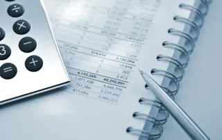 Close-up of calculator, pen, and financial ledger—Smith Marion Accounting Services.