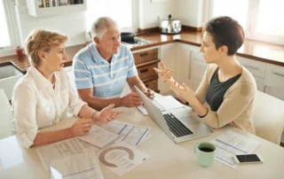 Older couple meets advisor at kitchen table to review documents and plan finances for tax season