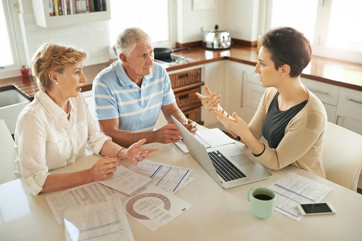 Older couple meets advisor at kitchen table to review documents and plan finances for tax season