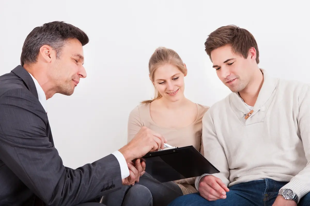Advisor meets young couple, explaining 3 considerations before choosing a private fiduciary indoors.