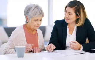 Advisor reviews finances with older woman, illustrating 4 ways to watch parents’ financial well-being