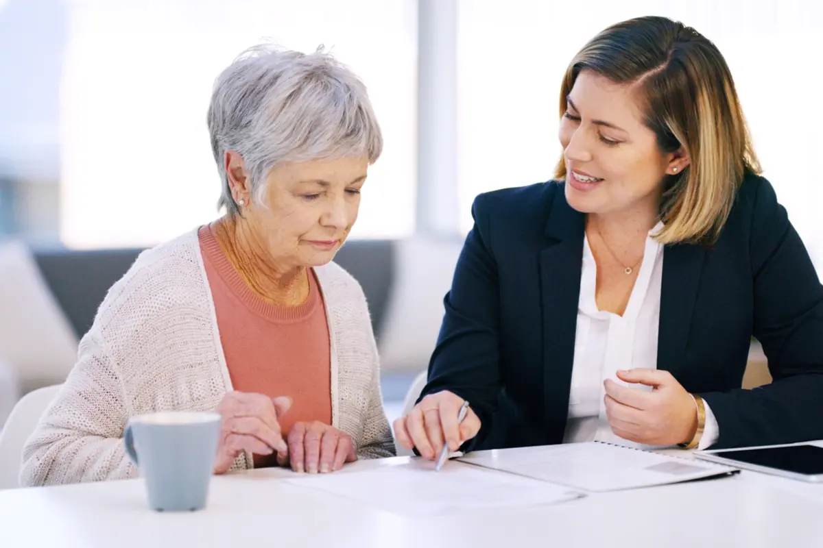 Advisor reviews finances with older woman, illustrating 4 ways to watch parents’ financial well-being