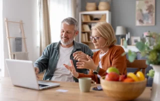 Older couple at laptop discussing 6 senior scams to be aware of in 2020 at home