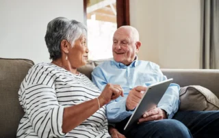 Senior couple reviews tablet while discussing Transitioning Your Elderly Parents’ Finances together.