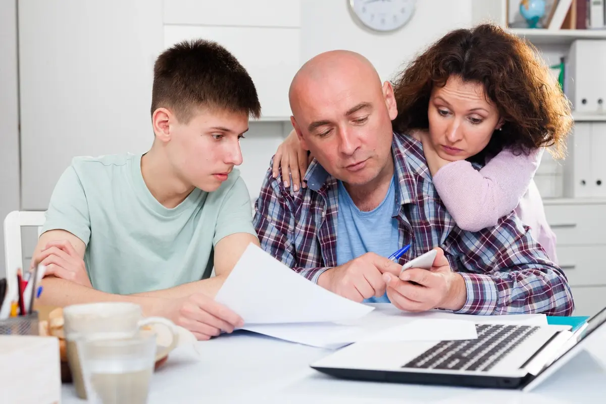 Family Pressures & Responsibilities When You Are the Trustee to Your Parent’s Trust Family reviews trustee paperwork and finances together at home table with laptop and documents open