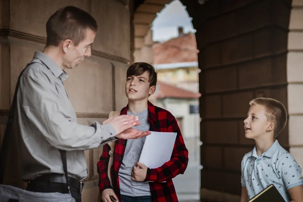 Man speaks with two boys about Helping Minors as Guardians of Their Estates outside building