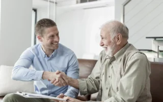 An elderly person and their child holding hands and working together after their child learned the answer to, How do you talk to an aging parent about finances.