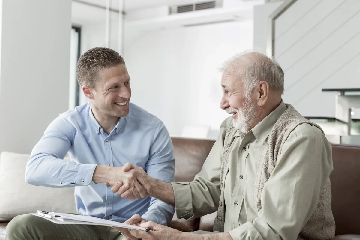 An elderly person and their child holding hands and working together after their child learned the answer to, How do you talk to an aging parent about finances.