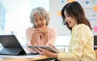 Older woman reviews tablet with advisor while learning how to help aging parents manage finances