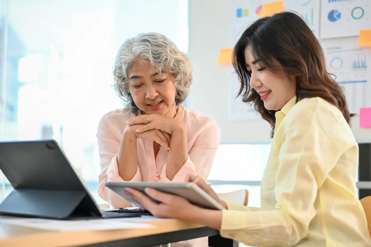 Older woman reviews tablet with advisor while learning how to help aging parents manage finances