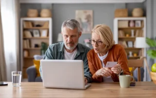 Older couple looks concerned at laptop, illustrating most popular senior scams in 2021