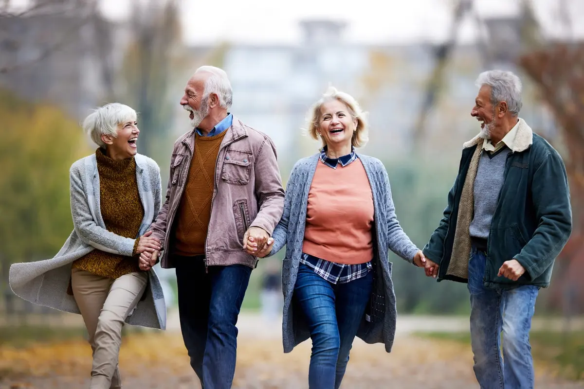 Four seniors walk outdoors in coats, smiling and enjoying senior-friendly activity ideas for winter