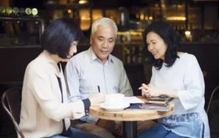 Three adults discuss the difference between a power of attorney and health care proxy over coffee