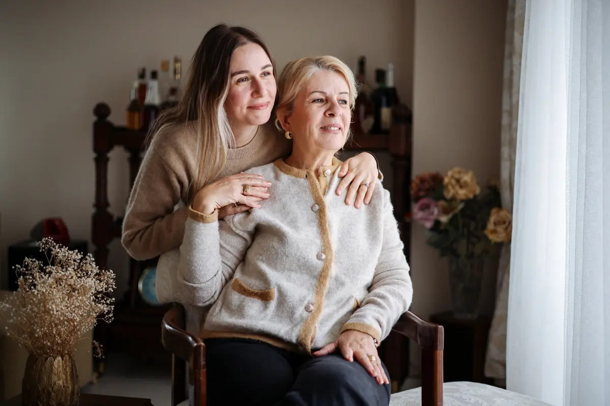 Adult daughter comforts older woman, illustrating conservatorship support in a home setting