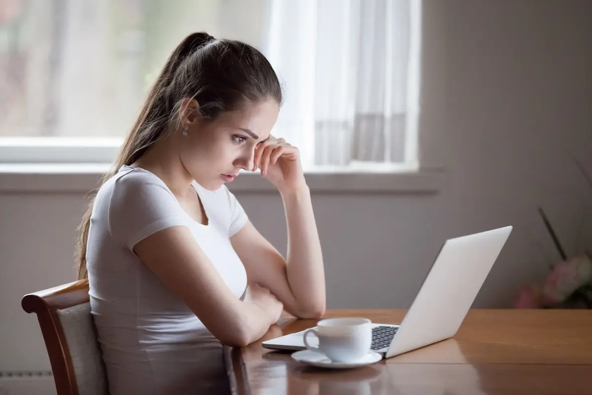 Top Scams to Look Out For in 2022: worried woman reviews laptop warnings at home