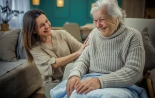 Cheerful mature woman embracing her senior mother at home while considering hiring a caregiver for elderly parent support.