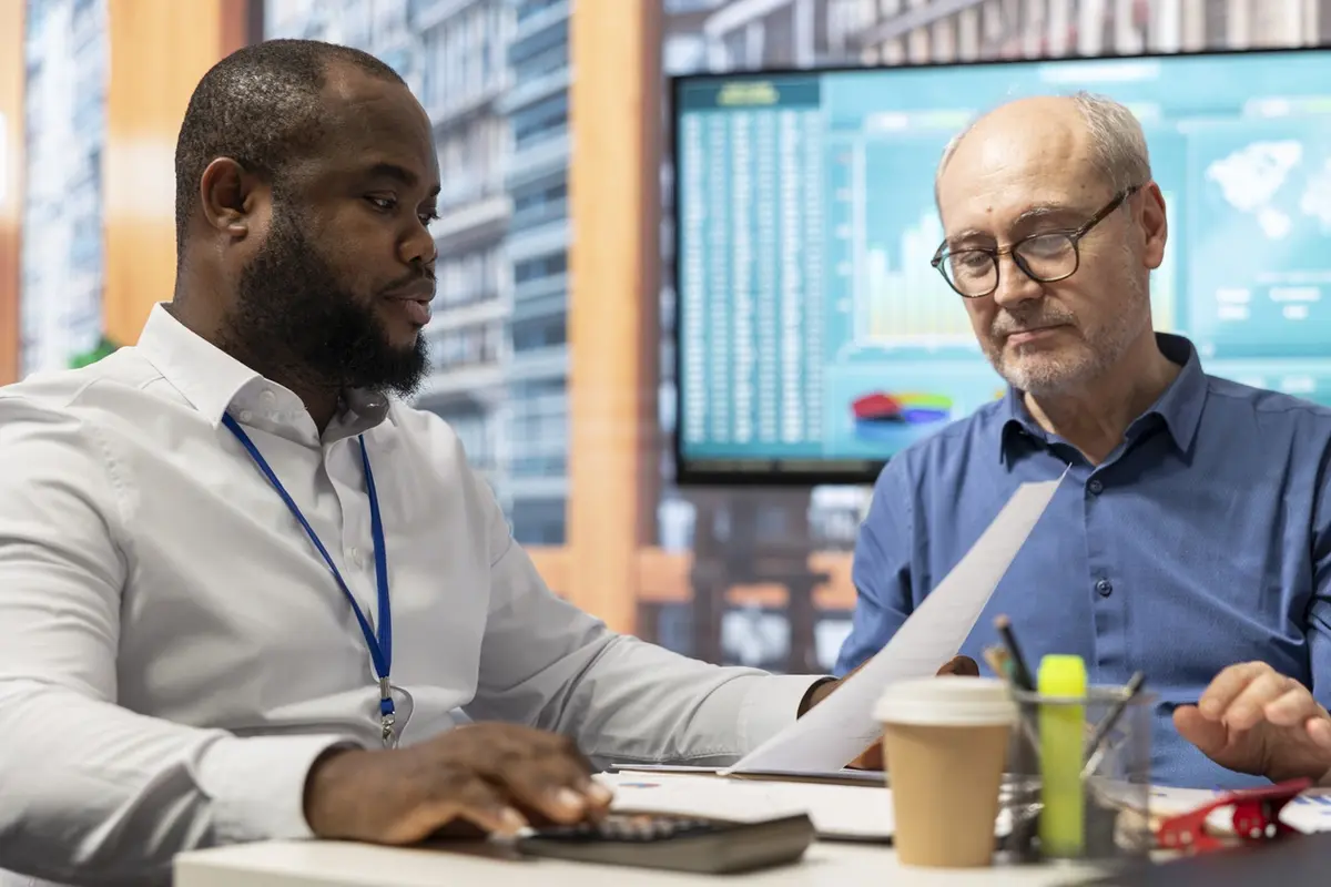Timeshares and Trust Planning for Senior Clients Financial banker using a calculator with senior clients to review timeshares, trust planning, and estate obligations.