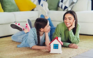 Mother and daughter with a model house representing adding a child to your home title.