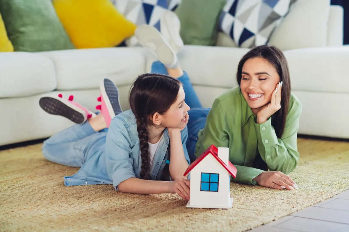 adding-a-child-to-your-home-title Mother and daughter with a model house representing adding a child to your home title.